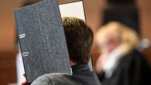 Der im Staufener Kindesmissbrauchsfall verurteilte Bundeswehrsoldat Knut S. verbirgt sein Gesicht zu Prozessbeginn hinter einem Aktenordner. Das Verbrechen wurde über eine Pädophilenplattform im Darknet angebahnt. Foto: dpa