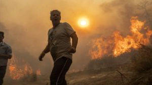 Ein Einheimischer flieht vor den Flammen von einem Waldbrand im Dorf Gennadi. Foto: AP/dpa/Petros Giannakouris