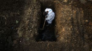 Ein Mann im Schutzanzug hebt im indischen Gauhati Erde aus, um die Leiche einer Person zu begraben, die an Covid-19 gestorben ist. Foto:  
