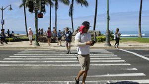 Ein Mann überquert in Honolulu einen Zebrastreifen und schaut dabei auf sein Smartphone. Wir er erwischt, kann das bis zu 35 Dollar kosten. Foto: AP