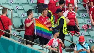 Zwei Ordner wollen diesen dänischen Fans offenbar eine Regenbogen-Fahne abnehmen. Foto: AFP/DARKO VOJINOVIC