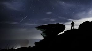 Ein Mann beobachtet einen Meteor über der Felsformation Brimham Rocks während des Geminiden-Meteoritenschauers. Foto: picture alliance/dpa/PA Wire/Danny Lawson