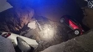 Die zwei geparkten Autos liegen in dem Erdloch. Foto: Polizia Roma Capitale/dpa