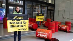 Mit roten Ölfässern protestieren Aktivisten von Greenpeace vor der Zentrale von DWS Investment in Frankfurt gegen die Investitionspolitik des Fonds. Foto: Boris Roessler/dpa