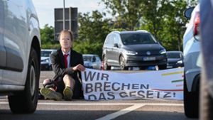 Ein Mitglied der Klimaschutzbewegung „Letzte Generation“ nimmt in Dresden am Freitagmorgen an einer Sitzblockade an der Autobahnabfahrt am Elbepark teil. Foto: dpa/Robert Michael