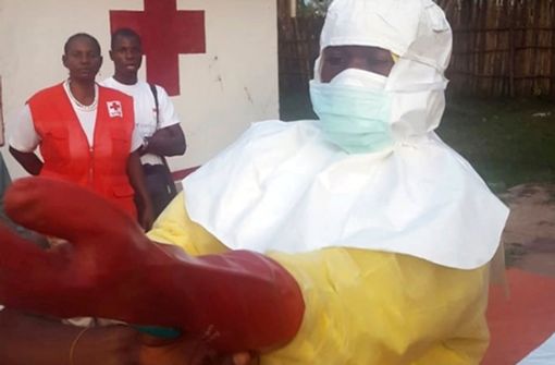 Ein Mitarbeiter vom Roten Kreuz zieht im Vorfeld der Suche nach Infizierten des Ebola-Virus Schutzkleidung an. Bis Freitag gingen die Behörden im Kongo von 45 möglichen Fällen aus. 25 Menschen sind bislang gestorben. Foto: dpa
