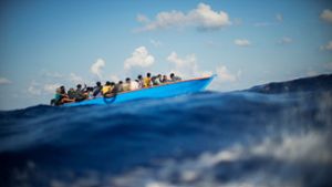 Migranten sitzen in einem Holzboot im Mittelmeer nahe der Insel Lampedusa: Die kleine Insel gehört seit Jahren zu den Brennpunkten illegaler Migration (Archivfoto). Foto: Francisco Seco/AP/dpa