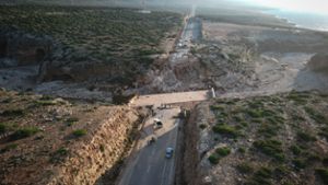 Diese Luftaufnahme zeigt Menschen, die auf der zerstörten Autobahn zwischen Darnah und Sousse im Osten Libyens stehen. Die Autobahn war ursprünglich mit einer Brücke verbunden, die bei den jüngsten schweren Überschwemmungen zerstört wurde.  Foto: Ibrahim Hadia al-Majbri/XinHua/dpa