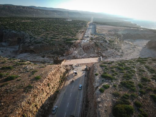 Diese Luftaufnahme zeigt Menschen, die auf der zerstörten Autobahn zwischen Darnah und Sousse im Osten Libyens stehen. Die Autobahn war ursprünglich mit einer Brücke verbunden, die bei den jüngsten schweren Überschwemmungen zerstört wurde.  Foto: Ibrahim Hadia al-Majbri/XinHua/dpa