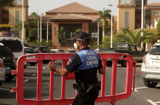 Eine Polizistin setzt eine Sperre, die den Zugang zum Hotel H10 Costa Adeje Palace auf Teneriffa blockiert. Nach einem bestätigten Coronavirus-Fall ist das Hotel unter Quarantäne gestellt worden. Foto: dpa/Uncredited