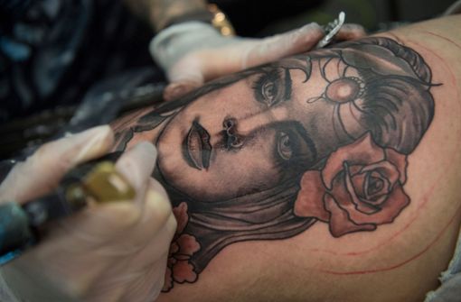 Eine Frau lässt sich auf der Internationalen Tattoo-Convention in Frankfurt am Main ein weibliches Gesicht in den Oberschenkel stechen. Foto: Boris Roessle