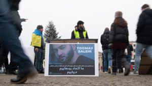 Protestaktion gegen Irans Staatsführung auf dem Pariser Platz in Berlin. Auf dem Plakat ist der Rapper Salehi zu sehen. Foto: Paul Zinken/dpa