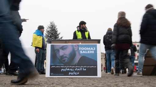 Protestaktion gegen Irans Staatsführung auf dem Pariser Platz in Berlin. Auf dem Plakat ist der Rapper Salehi zu sehen. Foto: Paul Zinken/dpa