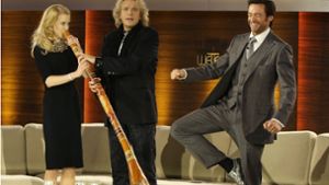 Nicole Kidman versucht sich am Didgeridoo, während Hugh Jackman (rechts) auf einem Bein balanciert. Foto: AP/Michaela Rehle