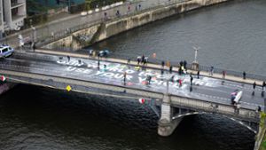 Klimaaktivisten der Bewegung Fridays for Future malen auf der Marschallbrücke in Berlin den Schriftzug Our world is on fire - use your voice!. Foto: Christophe Gateau/dpa