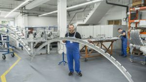 Ein Mitarbeiter hält im Werk Karlsruhe von Aircraft Philipp ein Blechteil für ein Flugzeugskelett. Foto: Aircraft Philipp Group/Wolfgang Stadler/ Fotografie