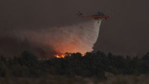 Ein Hubschrauber wirft Wasser über einem brennenden Wald in Griechenland ab. Foto: dpa/Achilleas Chiras