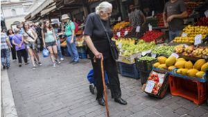 Eine Frau kauft auf einem Markt in Athen Lebensmittel ein. Foto: dpa/Socrates Baltagiannis