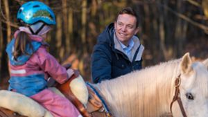 Der saarländische Ministerpräsident Tobias Hans (CDU) führt ein Pferd, auf dem eine seiner Töchter sitzt. Foto: dpa/Oliver Dietze