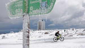 Ein Radfahrer ist auf dem schneebedeckten Brocken unterwegs. Foto: Matthias Bein/dpa