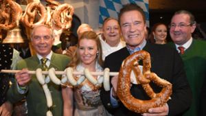 Arnold Schwarzenegger (rechts) freut sich gemeinsam mit Skifahrer Karl Schranz  und Heather Milligan über Riesenbrezel und Weißwürste. Foto: dpa