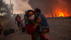 Ihre Kinder auf dem Arm versuchen die Flüchtlinge von Moria, den Flammen zu entkommen. Foto: AFP/ANGELOS TZORTZINIS
