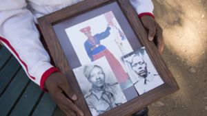 Uruanaani Scara Matundu, ein Vertreter der Herero-Gemeinde, zeigt in einem Park in Windhuk Fotos seiner Vorfahren. Foto: dpa/Gioia Forster