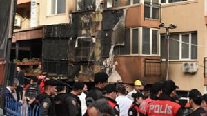 Einsatzkräfte stehen nach einem Brandausbruch vor einem teilweise verbrannten Gebäude. Foto: Safar Rajabov/XinHua/dpa
