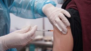 Ein junger Mann wird mit einer Booster-Dosis eines Corona-Impfstoffs in einem Impfzentrum in Potsdam gegen das Coronavirus geimpft. Foto: dpa/Jörg Carstensen