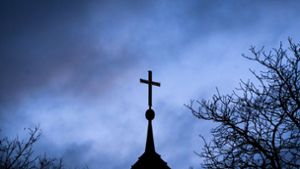 Dunkle Wolken über einem Kreuz einer Kirche: Einem der Missbrauchsopfer muss Schadenersatz gezahlt werden (Symbolbild). Foto: Julian Stratenschulte/dpa