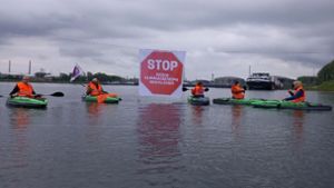 Klimaaktivisten der „Letzten Generation“ in Warnwesten blockieren mit Kajaks die Kanalzufahrt zum Ölhafen. Foto: dpa